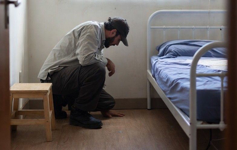 Pest control professional examining a small apartment room